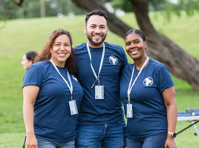 Three adults smiling and facing the camera.