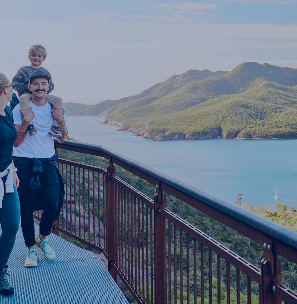  A young family walks on a scenic path, smiling. 