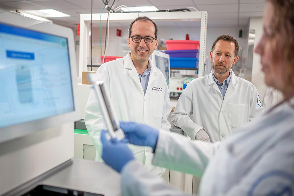 Three MSK staff members standing in a lab, looking at a computer monitor 